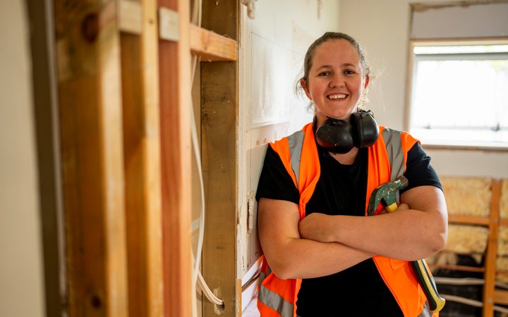 A smiling builder in hi-vis on a renovation site
